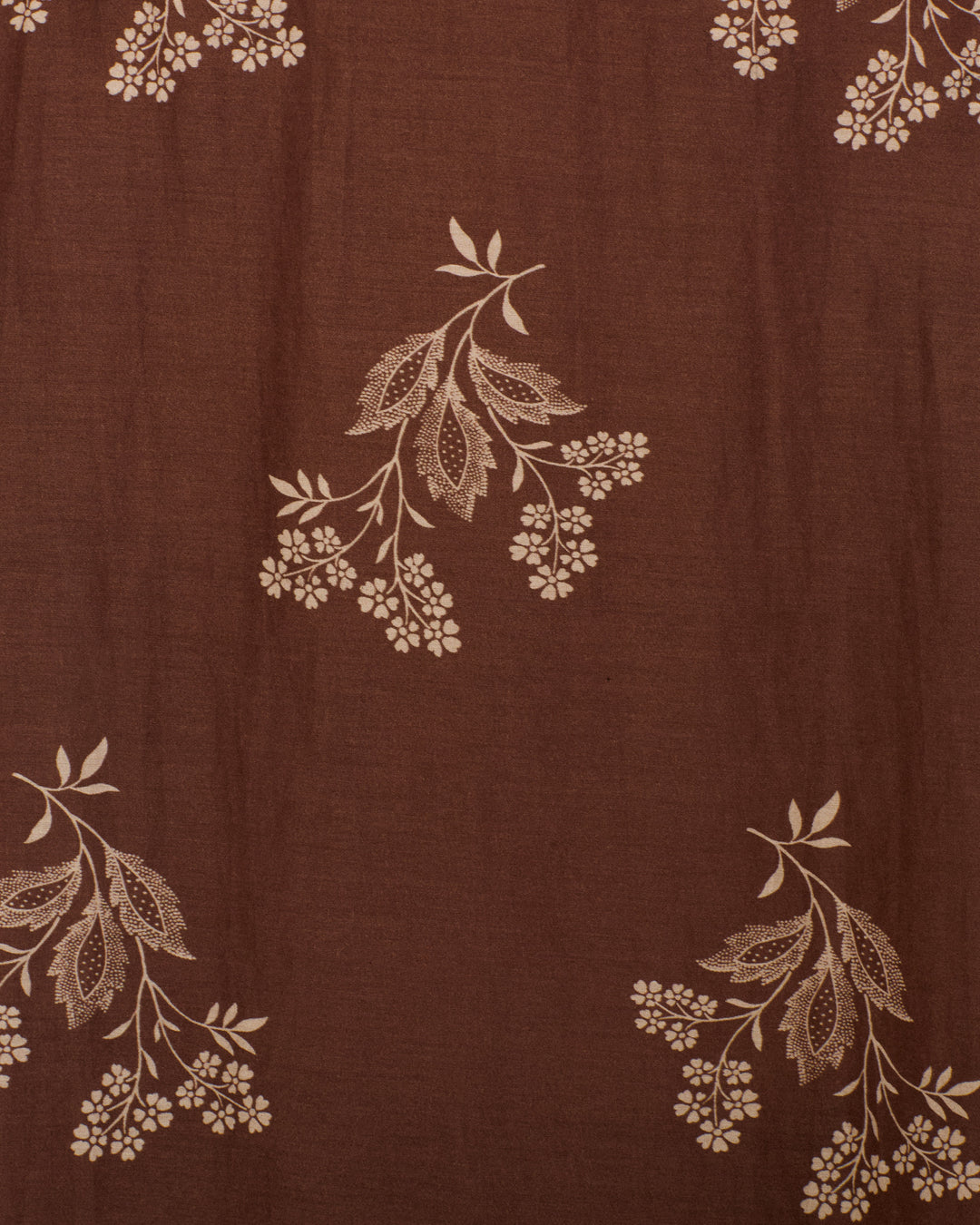 The Annabel Doe Elderflower Shirt features brown fabric adorned with a repeating pattern of beige floral and leaf designs, making it ideal for creating an elegant cotton-silk shirt with a ruffled collar and delicate puff shoulders.