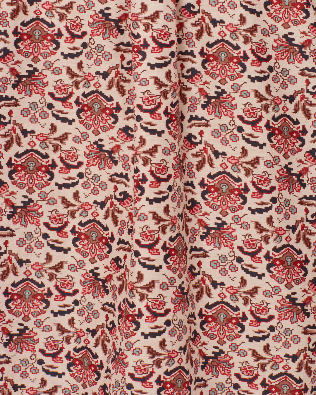 Close-up of the Annabel Horizon Kilim Shirt, showcasing its cotton-silk blend fabric with a detailed, repeating floral and abstract pattern in shades of red, brown, and black on a light beige background, and featuring a vertical central fold.