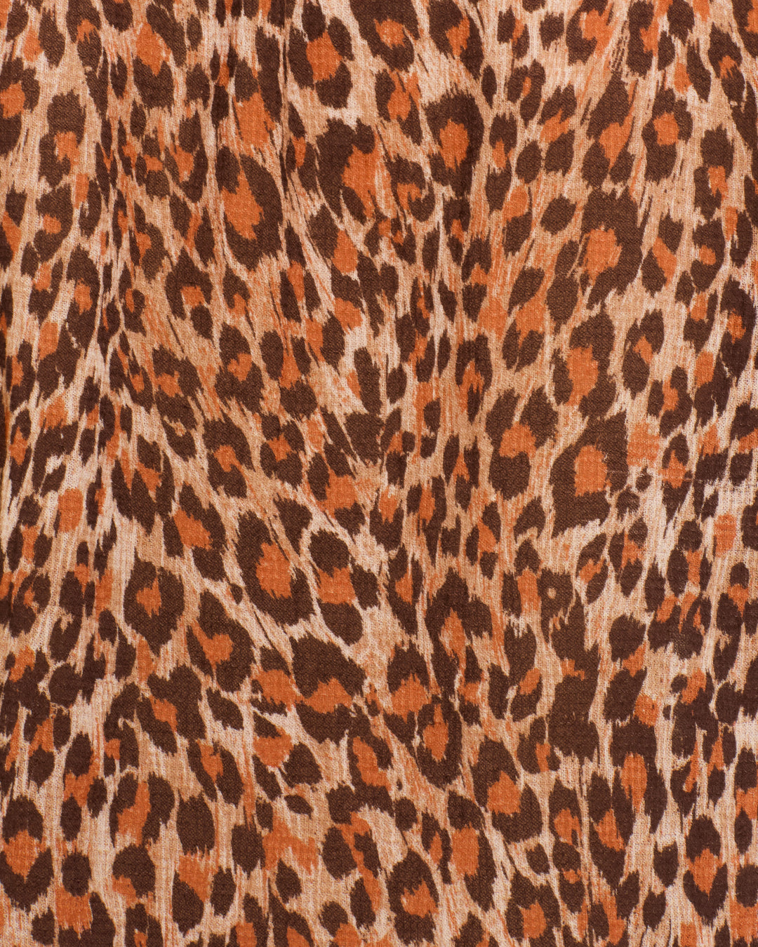 Close-up of the Artemis Leopard Trek Shirt fabric, showcasing its brown and orange leopard print pattern with irregular spots on a textured surface—ideal for crafting a bold statement shirt with puff sleeves or a delicate ruffled collar.