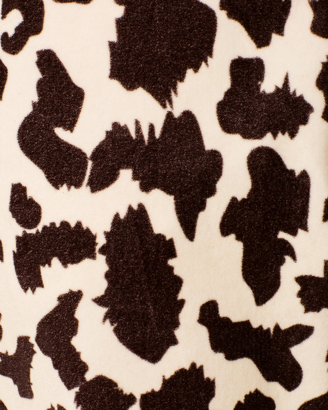 Close-up of the Bunny Leopard Steppe Jean, showcasing soft cotton velvet with an irregular brown and cream animal print pattern, reminiscent of cowhide or abstract camouflage, and subtle hints of leopard spots.