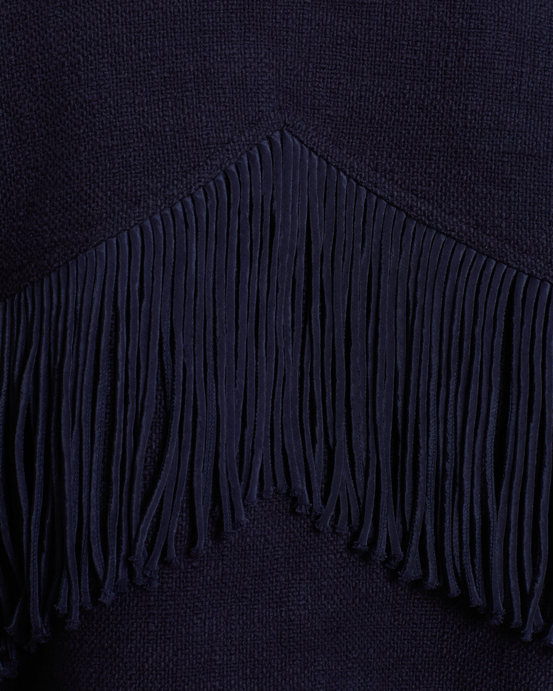 Close-up of dark blue fabric with a row of vertical Western fringing forming a V shape across the material, reminiscent of detailing found on the Court Indigo Night Jacket.