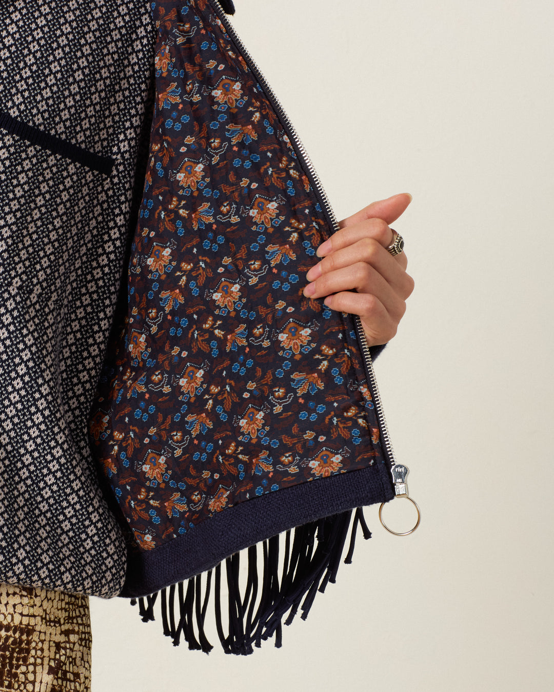 A person holds open the Court Indigo Night Jacket to reveal a brown and blue floral lining with Western fringing along the edge.