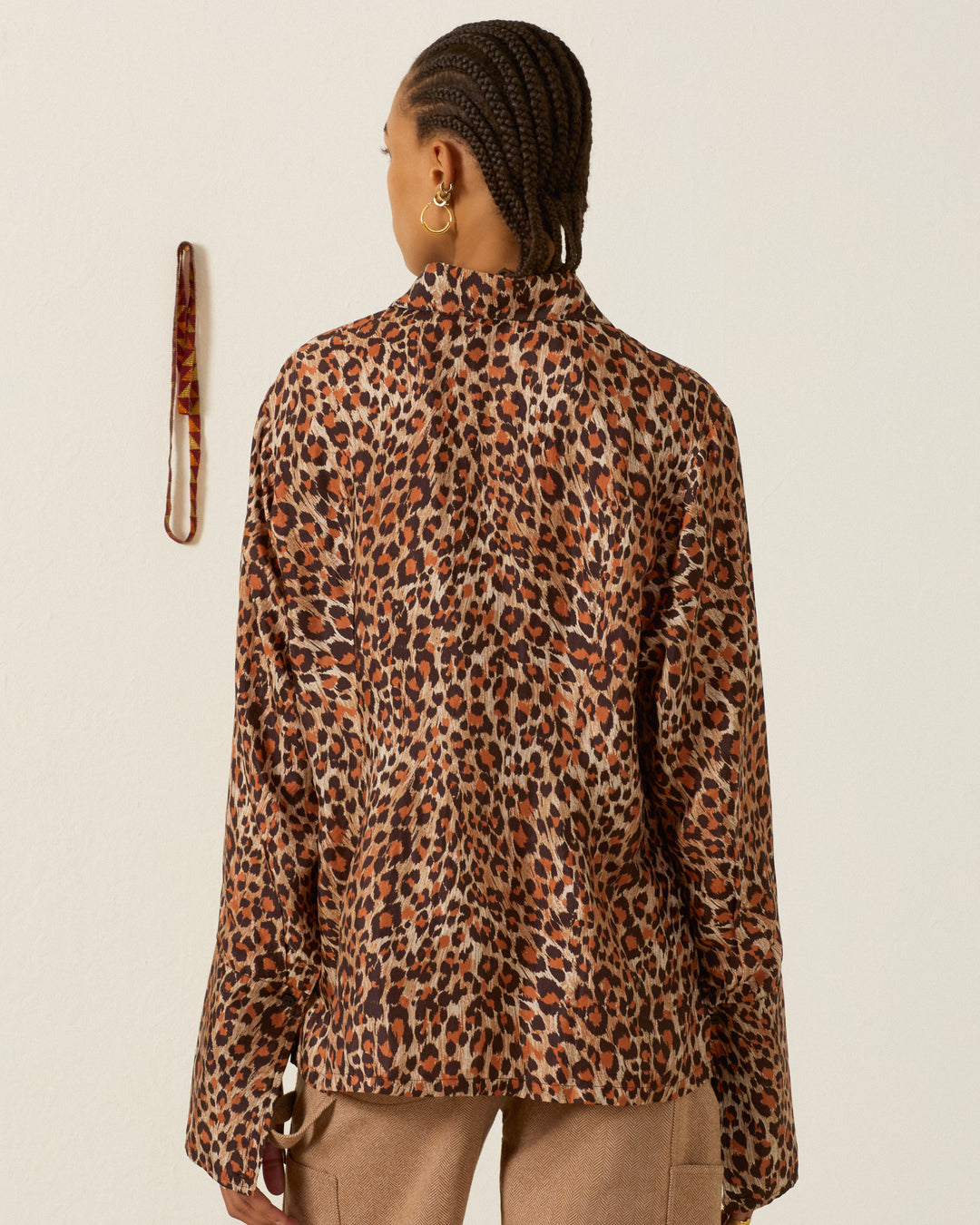 Back view of a person wearing a brown and black leopard print Dana Leopard Trek Silk Shirt with long sleeves.
