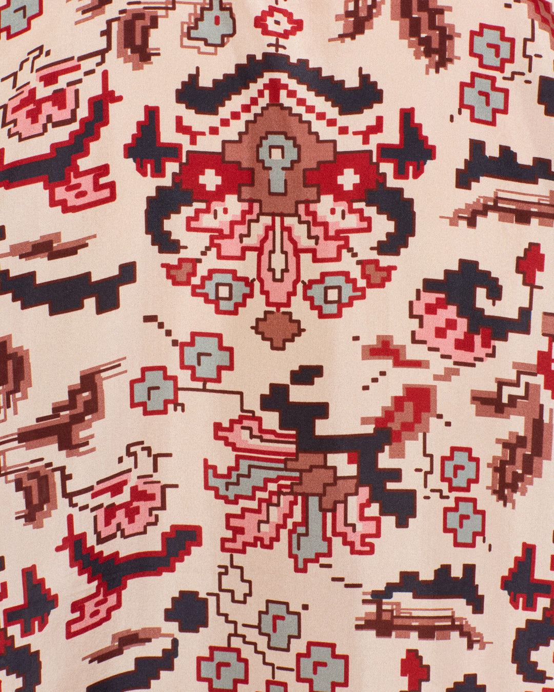Close-up of the Dana Horizon Kilim Silk Shirt, showcasing fabric with an abstract geometric pattern in red, blue, brown, and beige tones—highlighting repetitive shapes and pixel-like designs inspired by traditional kilim motifs.