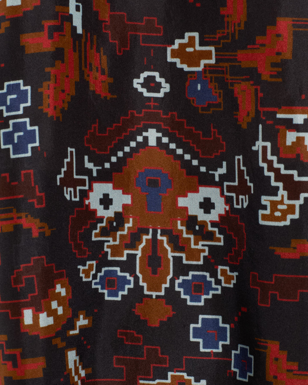Featuring kilim-inspired geometric motifs in red, blue, white, and brown on a black background, the Emery Indigo Kilim Silk Shirt showcases a textile pattern that evokes abstract digital and tribal art.