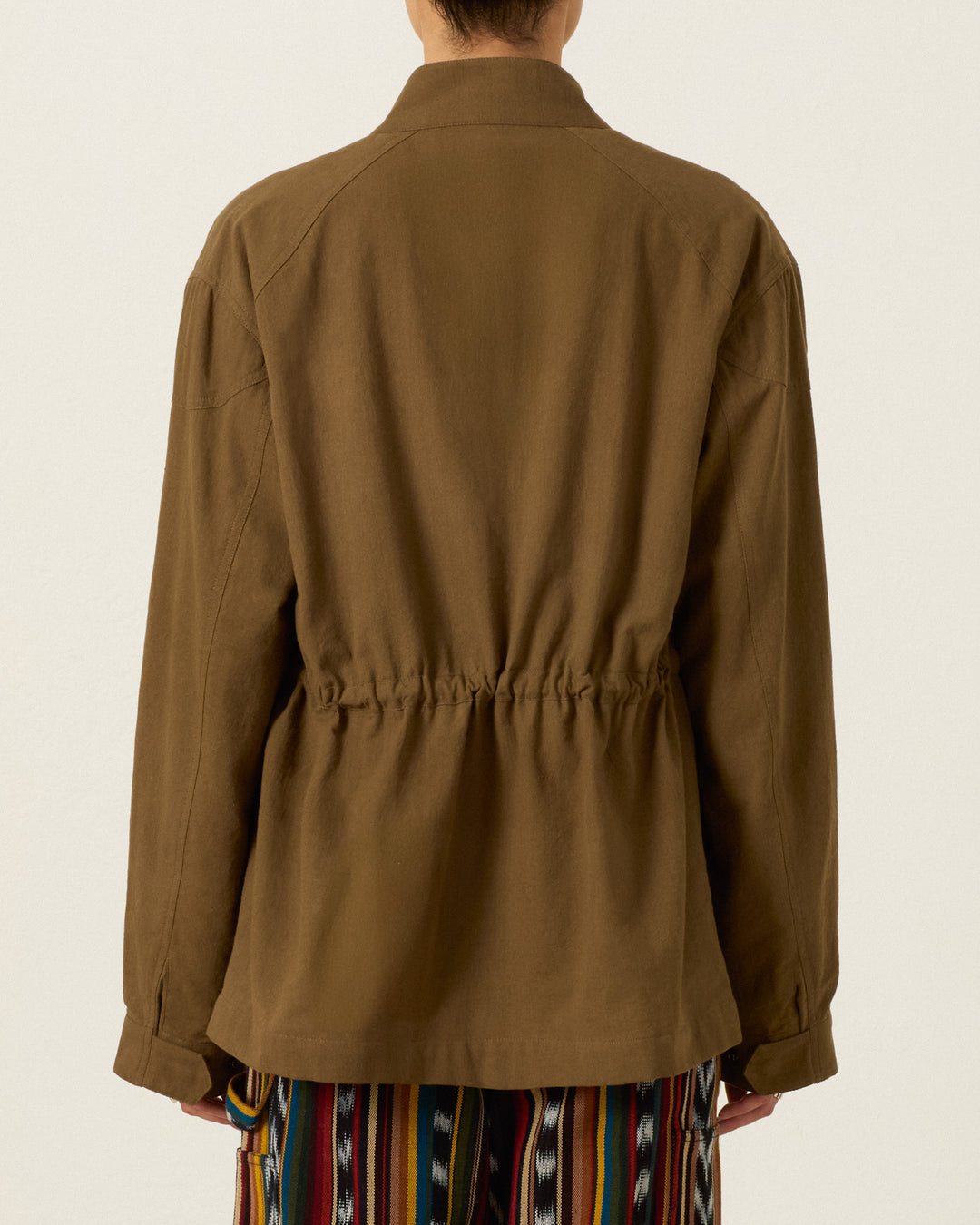 Back view of the olive-colored Evelyn Olive Branch Jacket, a hand-embroidered Khadi cotton utility jacket with a cinched waist.