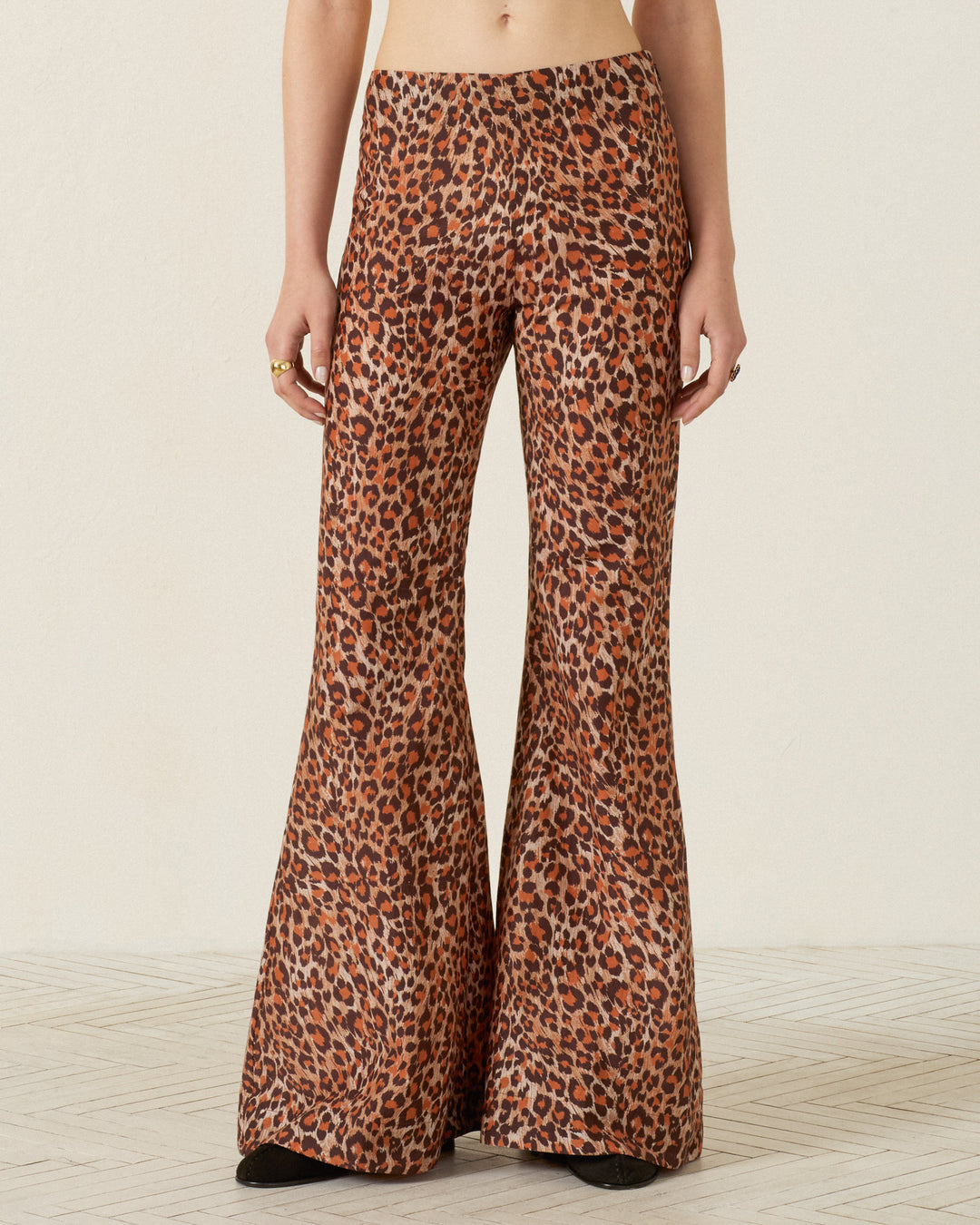 Wearing the Farah Leopard Trek Pant, which features a high-waisted fit and dramatic bell-bottom flare, this person stands against a plain background.