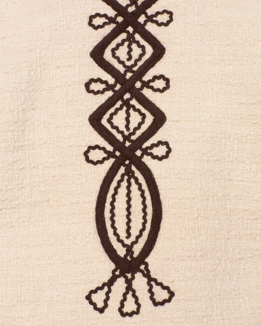 Close-up of the cream-colored, textured fabric of the Jude Bushland Cord Jacket, featuring a vertical and symmetrical black geometric pattern reminiscent of soutache embroidery.
