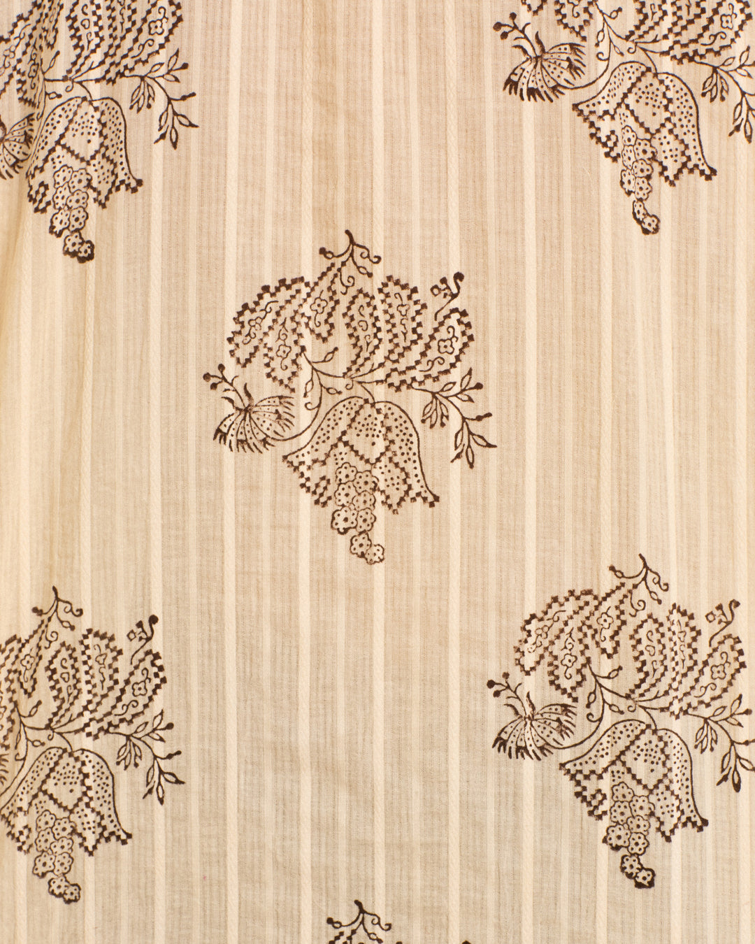 The Kiki Grapevine Stripe Shirt is a cream-colored cotton dobby shirt with vertical stripes, adorned with a repeated brown embroidered peacock and floral motif pattern that evokes an Edwardian silhouette.