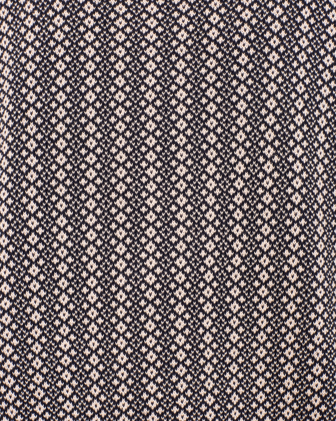 Close-up of the Lessi Cobblebud Knit Top, a vintage cropped polo featuring a black and white geometric motif with repeating diamond shapes arranged in rows across the fabric, highlighting its timeless appeal.