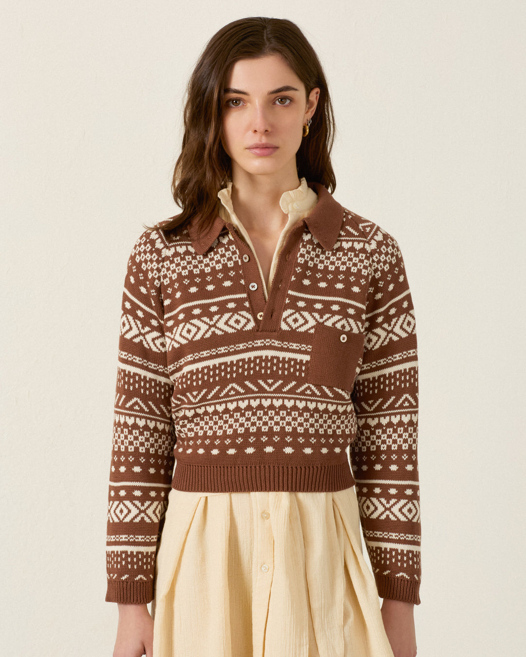 A woman wears the Liza Mocha Fair Isle Top over a beige collared dress, standing against a plain light background.