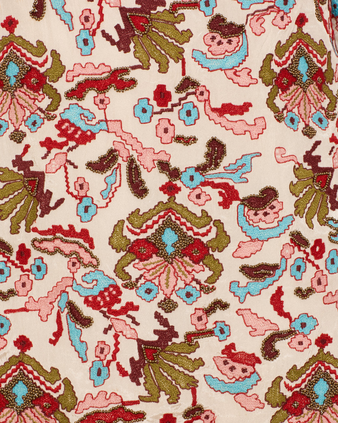 Close-up of the Narene Kilim Emblem Dress fabric, showcasing an embroidered floral and abstract pattern in red, green, brown, and blue on a cream background with subtle kilim-inspired motifs.