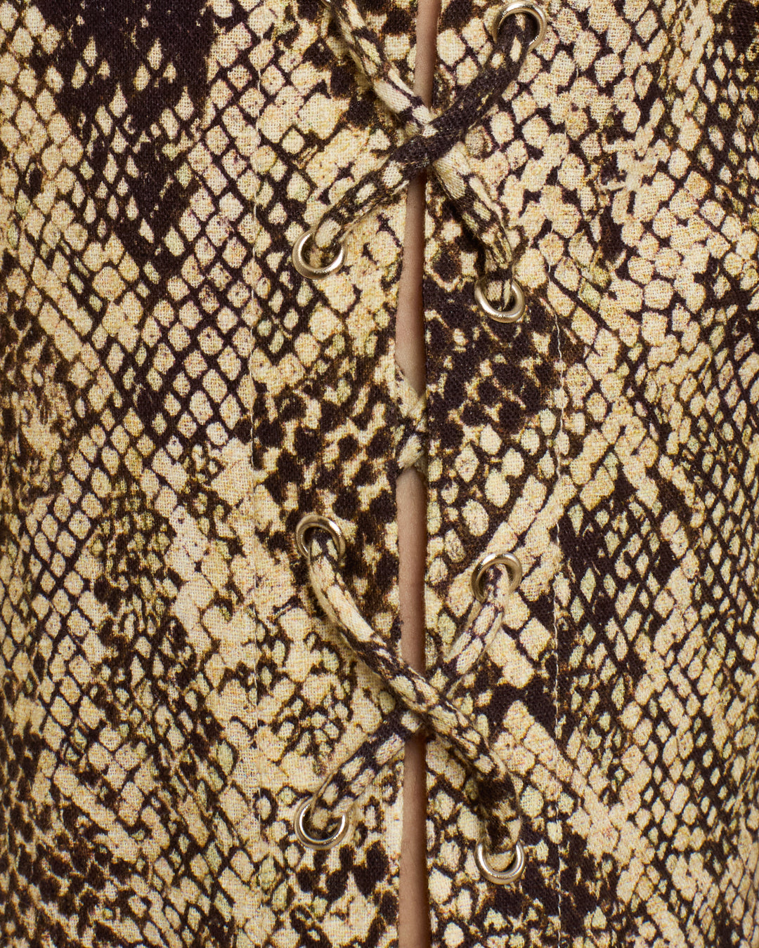 Close-up of the Razza Lemon Snakeskin Pant featuring brown and beige snakeskin print fabric with lace-up ties and gold eyelets.