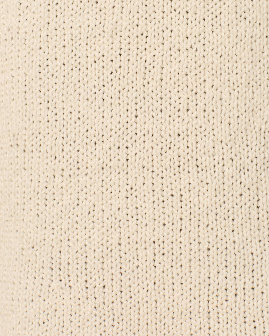 Close-up of the Renny Bone Fringe Dress, featuring beige knitted fabric with vertical rows of stitches that form a textured and uniform pattern across the surface—characteristic of an artisan-made, hand-knitted sweater dress crafted from soft Peruvian cotton.