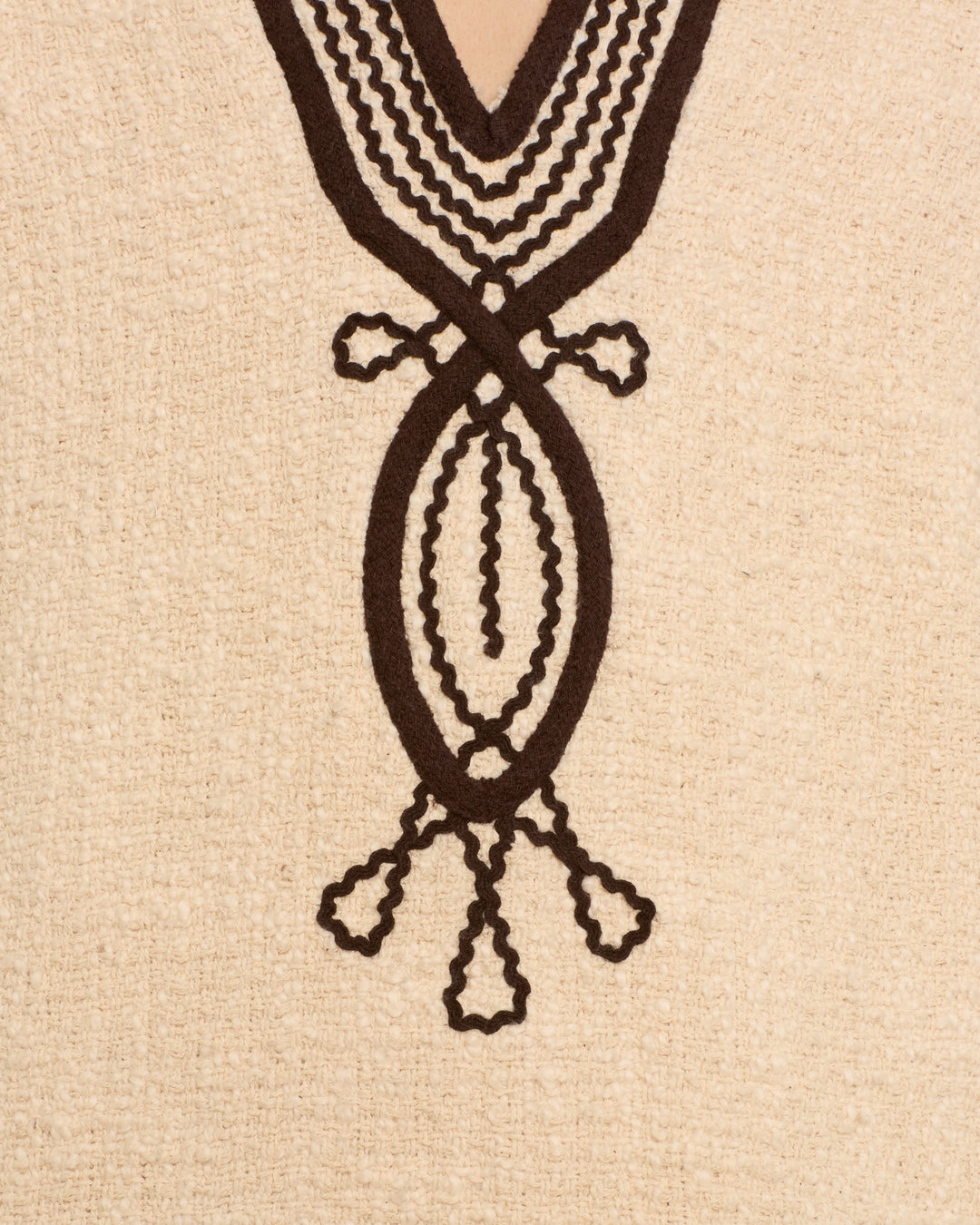 Close-up of the Rosie Bushland Cord Dress, a beige mini dress crafted from textured cotton bouclé and featuring a symmetrical black soutache embroidery design hand embroidered around the neckline.