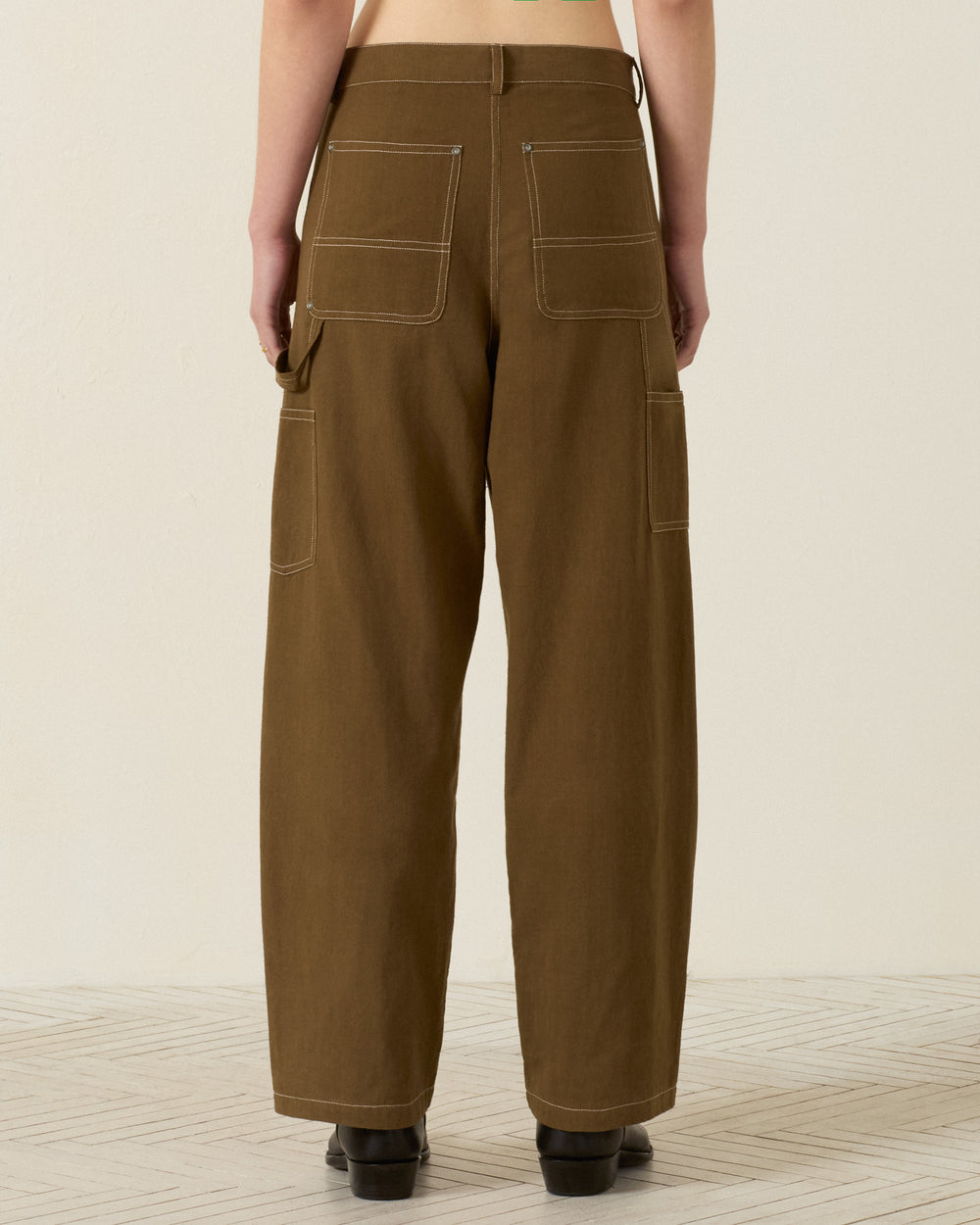 Back view of a person wearing the Scottie Olive Branch Pant—wide-leg painter pants in durable Khadi cotton with contrast stitching, large back patch pockets, and side utility loops for a classic workwear-inspired look.