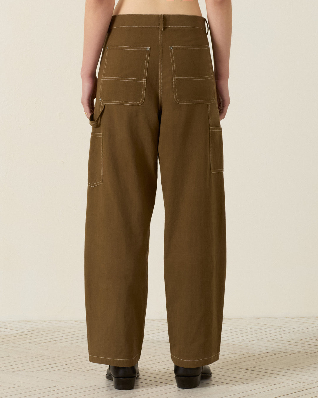 Back view of a person wearing the Scottie Olive Branch Pant—wide-leg painter pants in durable Khadi cotton with contrast stitching, large back patch pockets, and side utility loops for a classic workwear-inspired look.