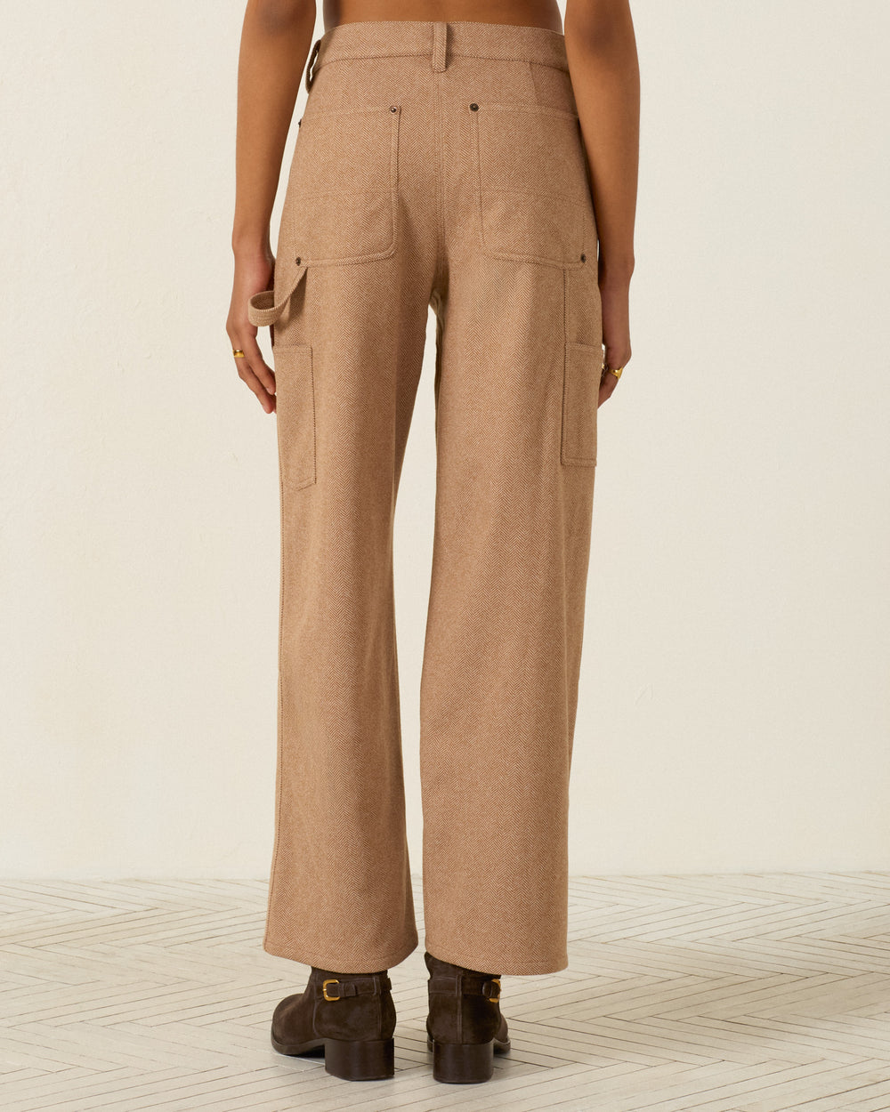 Back view of Scottie Savanna Sand wool herringbone straight-leg painter pants with utility pockets and a hammer loop, worn with dark brown ankle boots.
