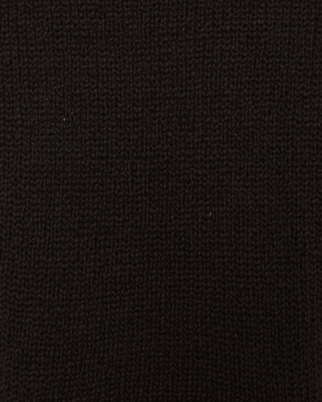 Close-up view of the Sonia Onyx Fringe Top, highlighting its black artisan-made knitted fabric and showcasing the intricate texture and stitch pattern.