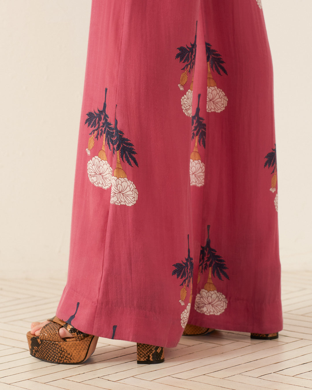 A person wearing Charlie Hibiscus Rose Pants and snakeskin platform sandals stands on a light-colored, patterned floor, exuding a vintage feel.