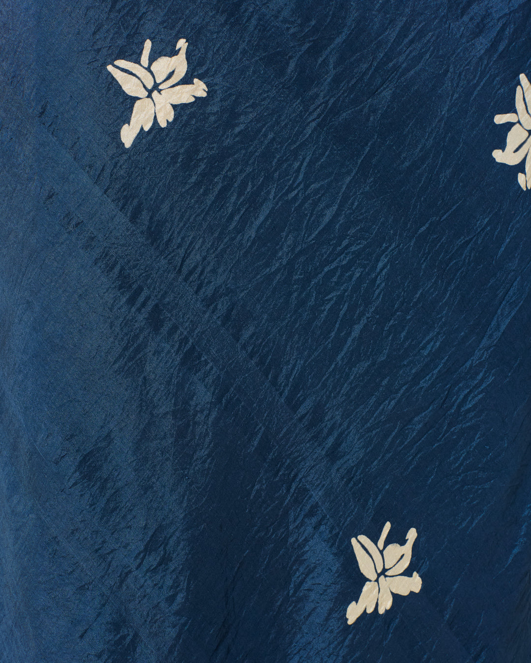 Close-up of dark blue textured fabric from the Adele Pacific Jasmine Dress, showing small white hand-block printed floral patterns scattered across the surface.