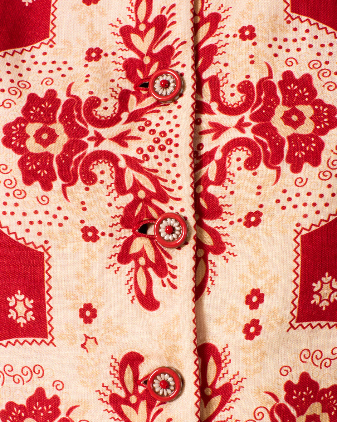 Close-up of the Rowan Lava Bandana Jacket in beige linen, showcasing a red floral and paisley print and handmade buttons down the center.