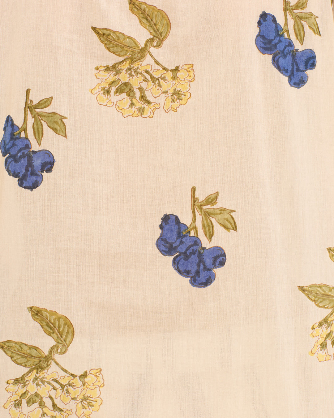 The Annabel Blueberry Flora Shirt is a beige cotton voile top with blue berry clusters and yellow flower prints, evenly spaced, and finished with a ruffled collar for a touch of elegance.
