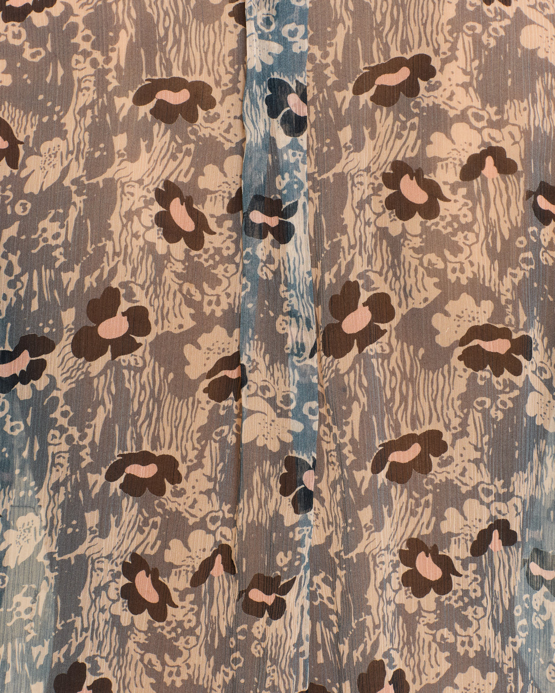 Close-up of fabric with an abstract brown, beige, and blue floral motif and a visible central seam, as seen on the Chance Water Flower Shirt—a perfect choice for showcasing its delicate pussy-bow ties in cupro-chiffon.