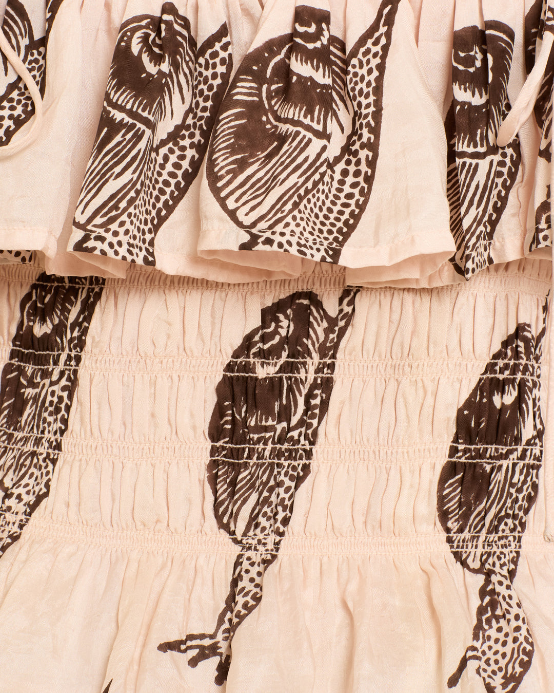 Close-up of beige silk fabric with brown snail print and gathered stitching showcases the intricate detail of the Claire Snail Study Silk Top, hand-block-printed for artisan appeal.