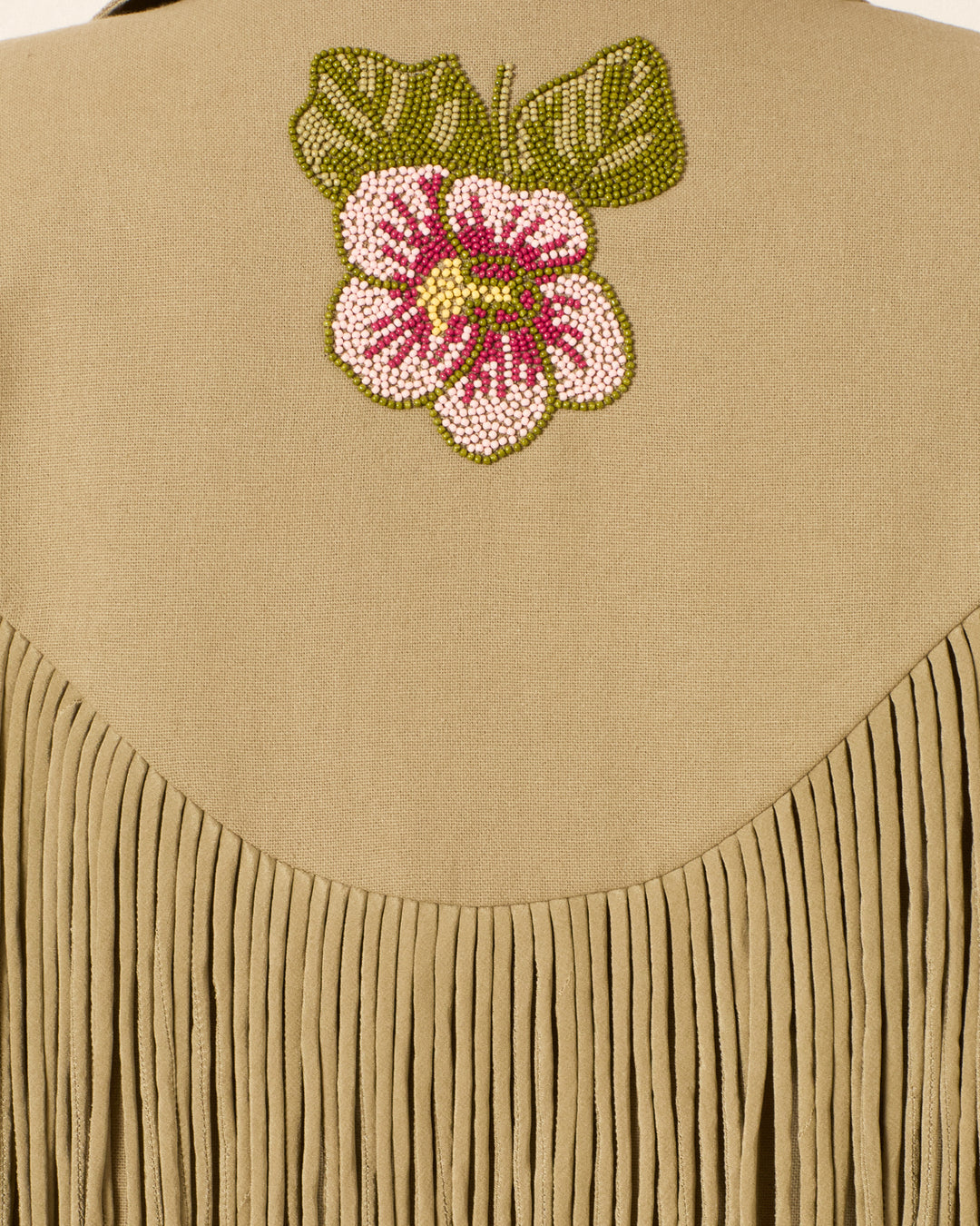 Jude Moss Fringe Jacket crafted from tan textured cotton, featuring fringe detail and a hand-beaded floral design with a pink and white flower accented by two green leaves.