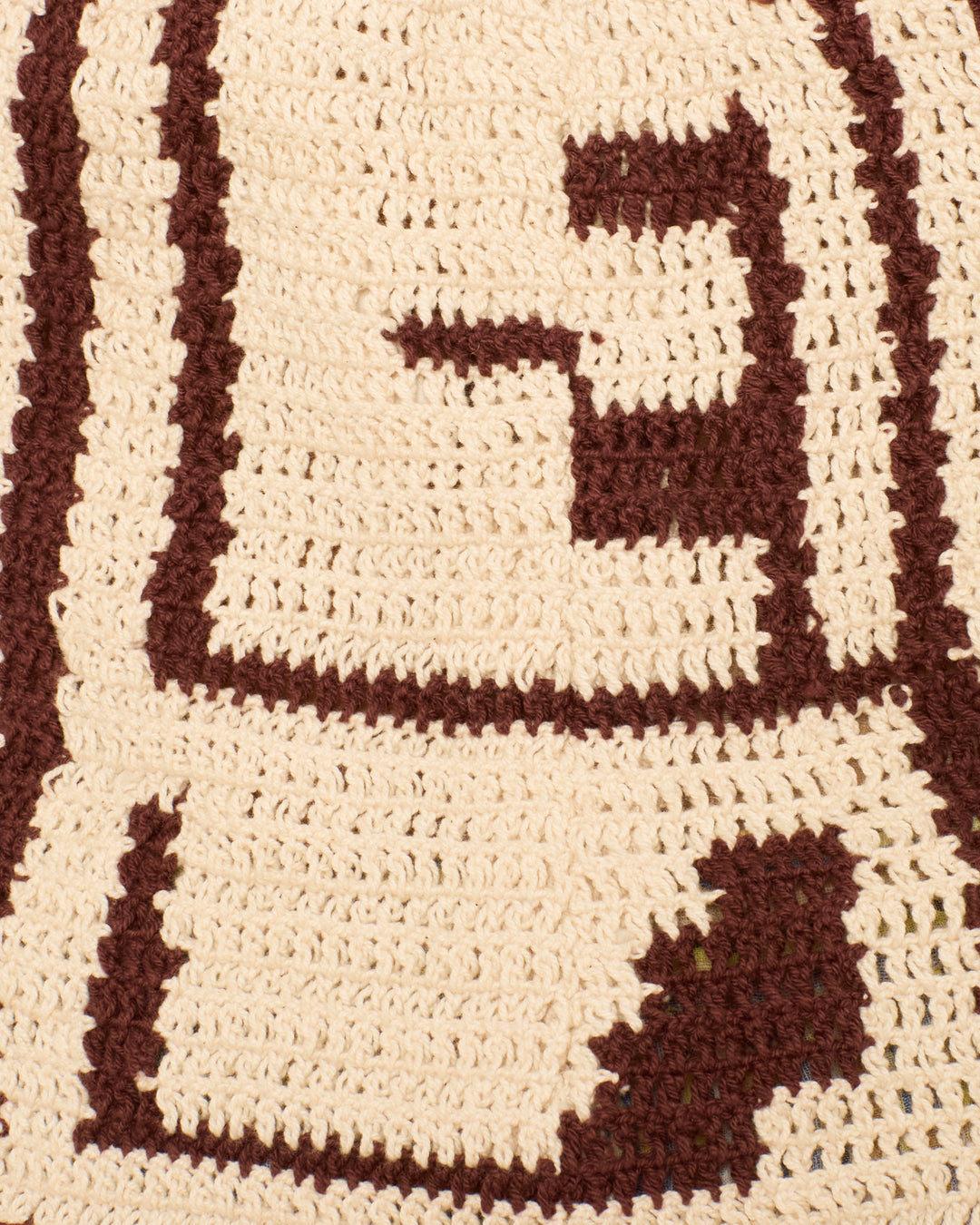 Close-up of the Knox Auburn Driftmap Top, a crocheted halter with a cream base and brown ikat-inspired geometric designs.