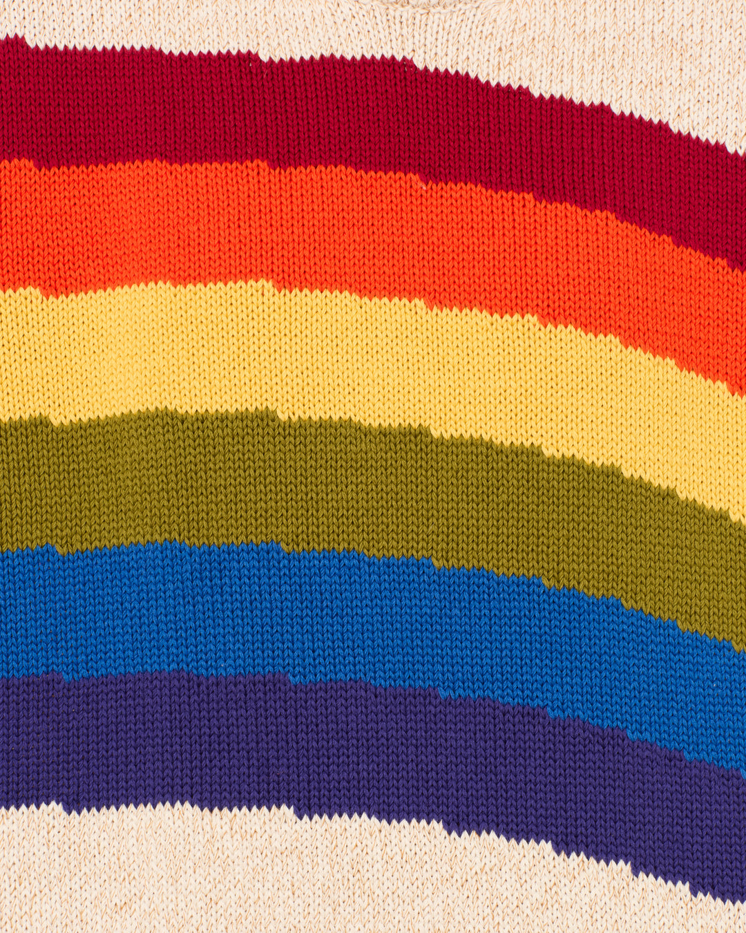 The Sammi Prism Knit Cardigan features horizontal rainbow stripes in red, orange, yellow, green, blue, and purple, made from soft organic Italian cotton for a sustainable touch.