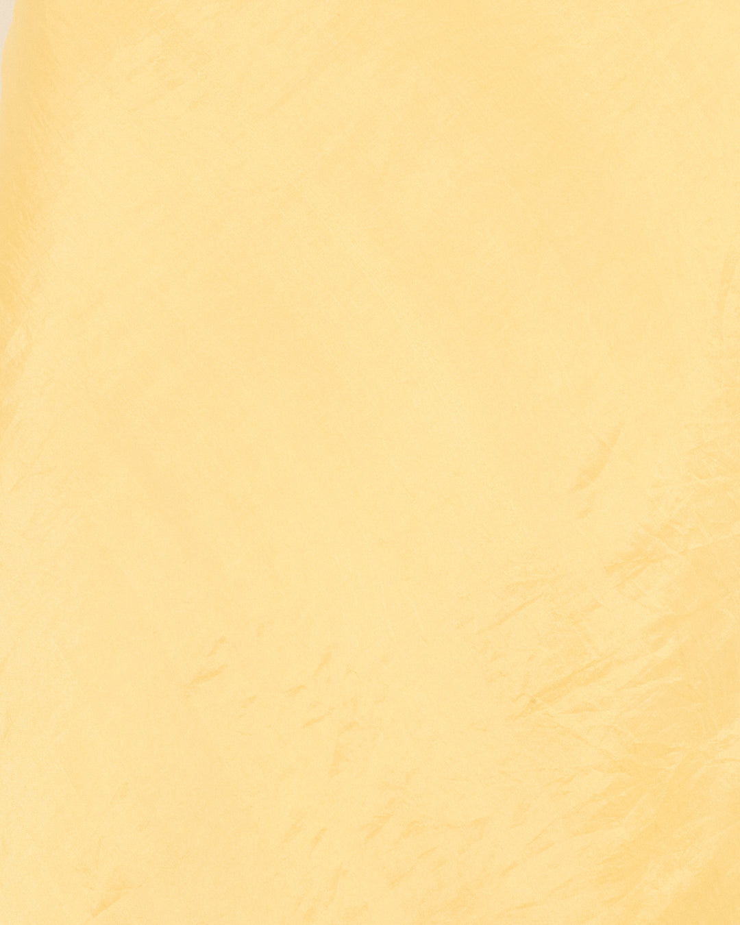 Close-up of the Lyra Sunlight Silk Skirt shows textured, crinkled yellow silk with subtle creases and artisan-crafted folds.