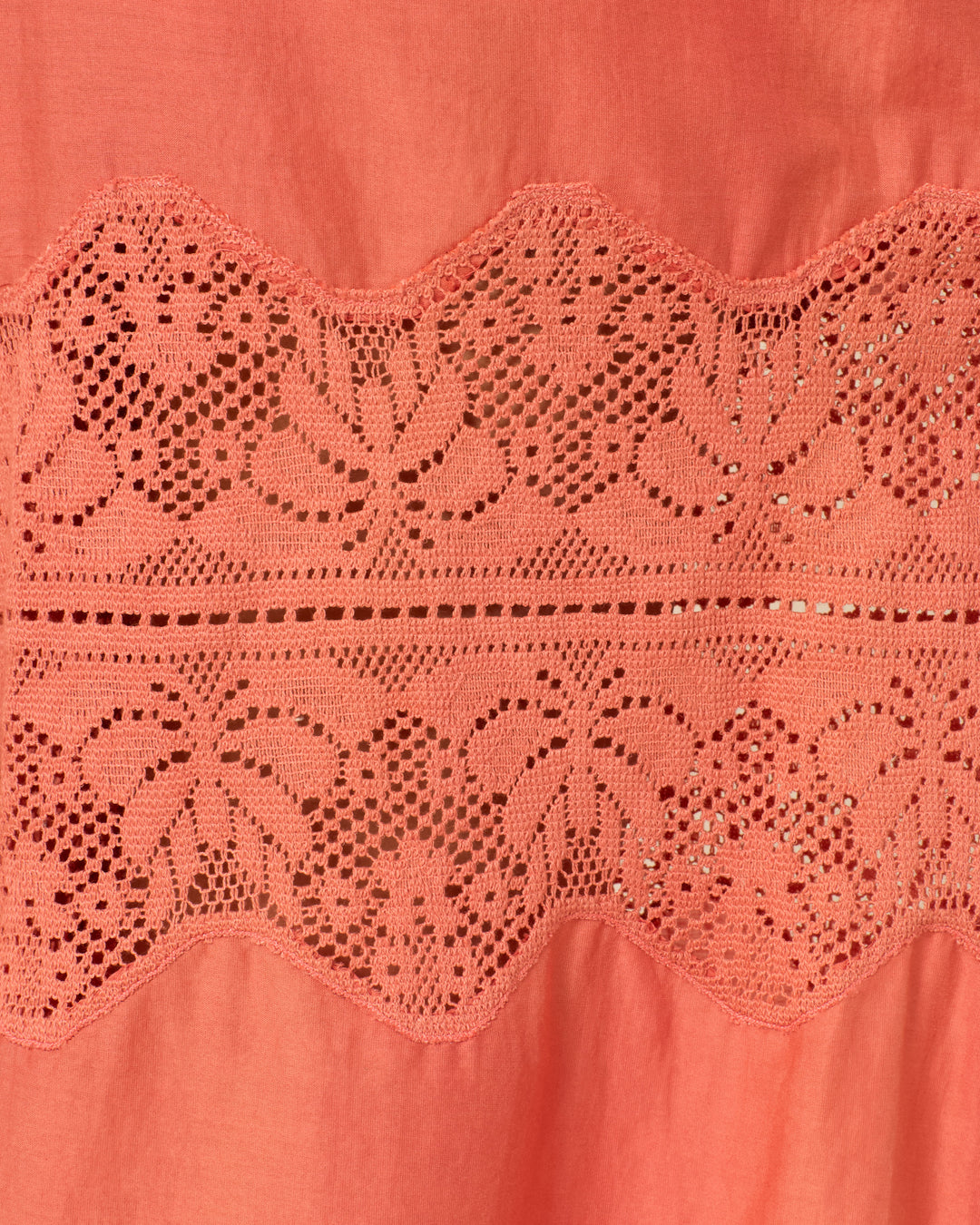 Close-up of the Margie Rouge Dust Pants coral cotton-silk blend fabric, highlighted by a horizontal cotton lace panel with an intricate repeating leaf pattern.