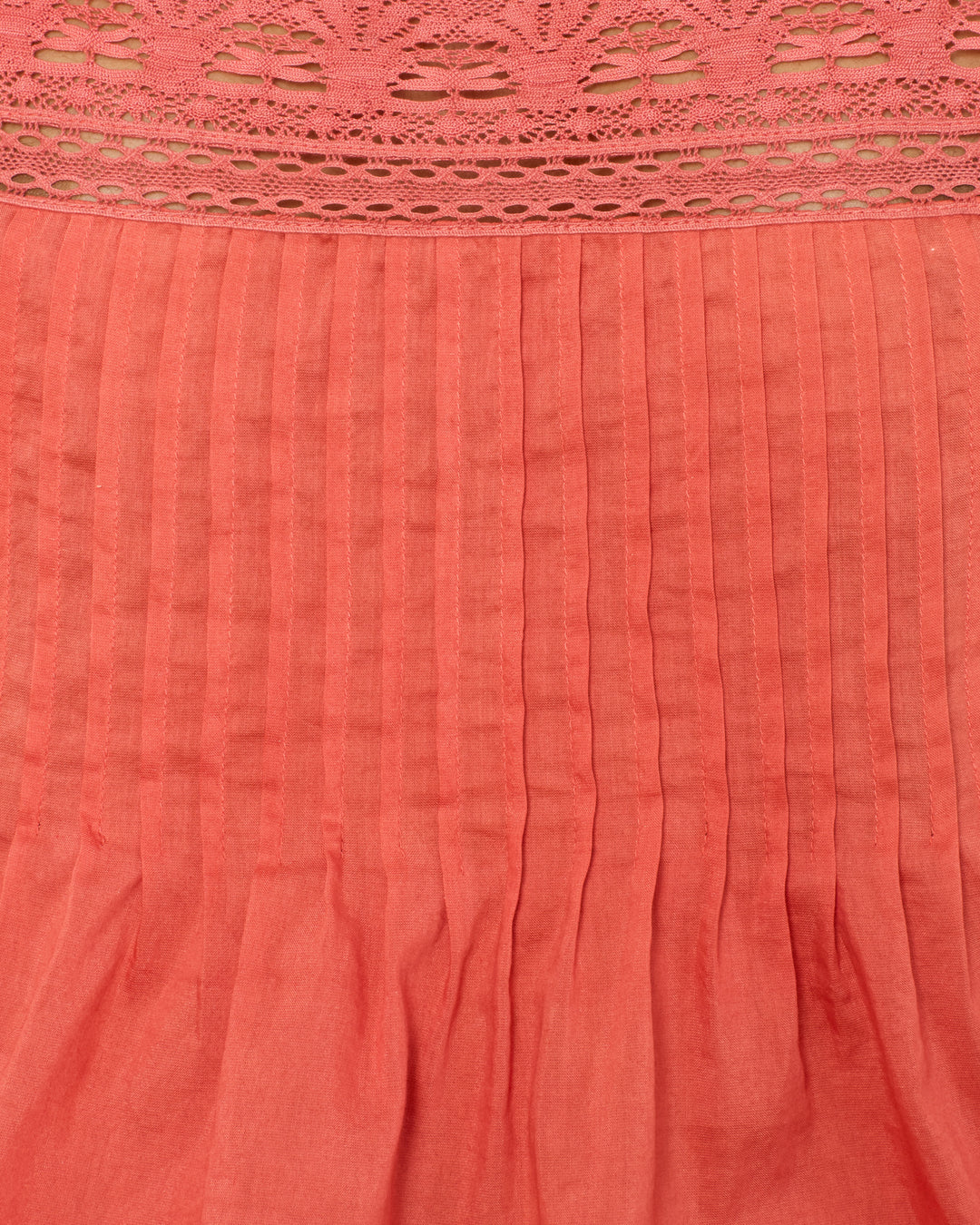 Close-up of the Mimi Rouge Dust Top, made from a coral cotton-silk blend with vertical stitched pleats, gathered bottom folds, and a decorative cotton lace panel at the top.