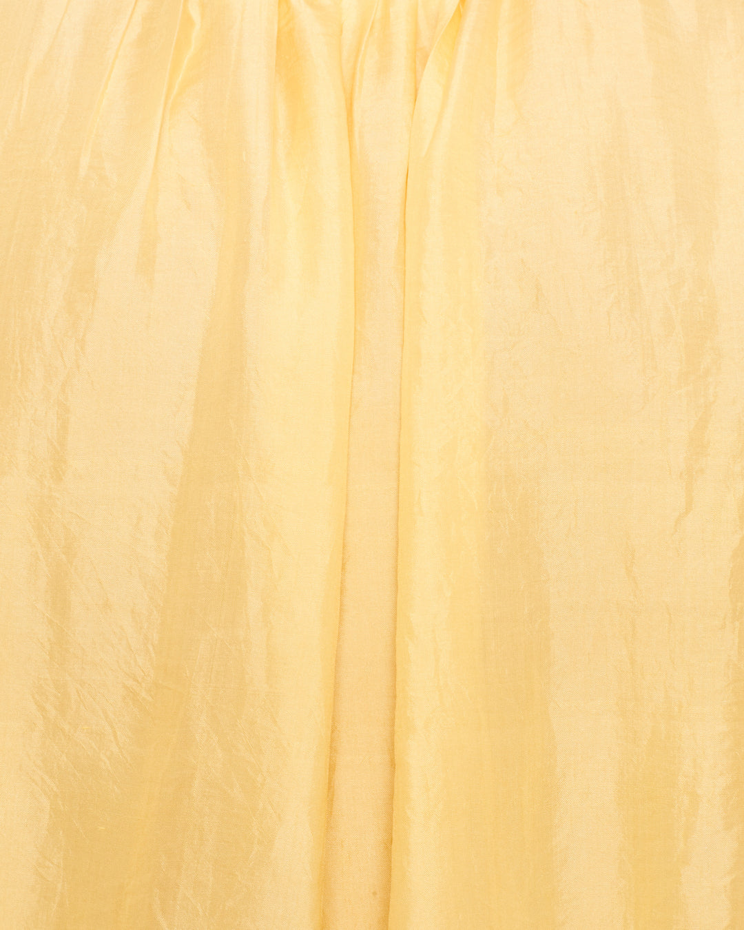 Close-up of gathered, light yellow, shiny fabric with subtle wrinkles and folds—ideal for the Nova Sunlight Silk Shirt.