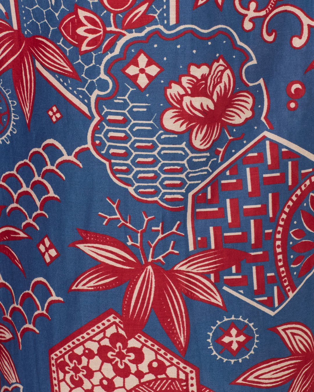 The Otto Delft Hive Pant features blue fabric with a geometric and floral wagara print in red and white, showcasing overlapping flowers, leaves, hexagons, and lattice shapes for a stylish cotton-silk look.