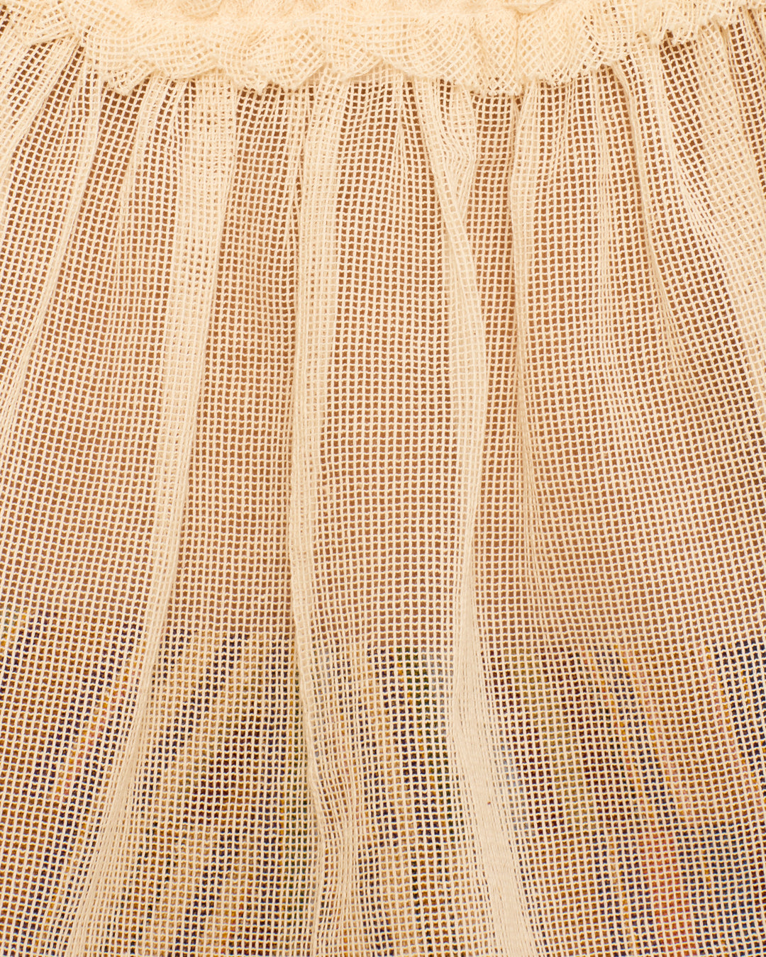 Close-up of the Tati Pearl Weave Top: a light beige cotton mesh design with vertical pleats, gathered top edge, and delicate ruffled trim.