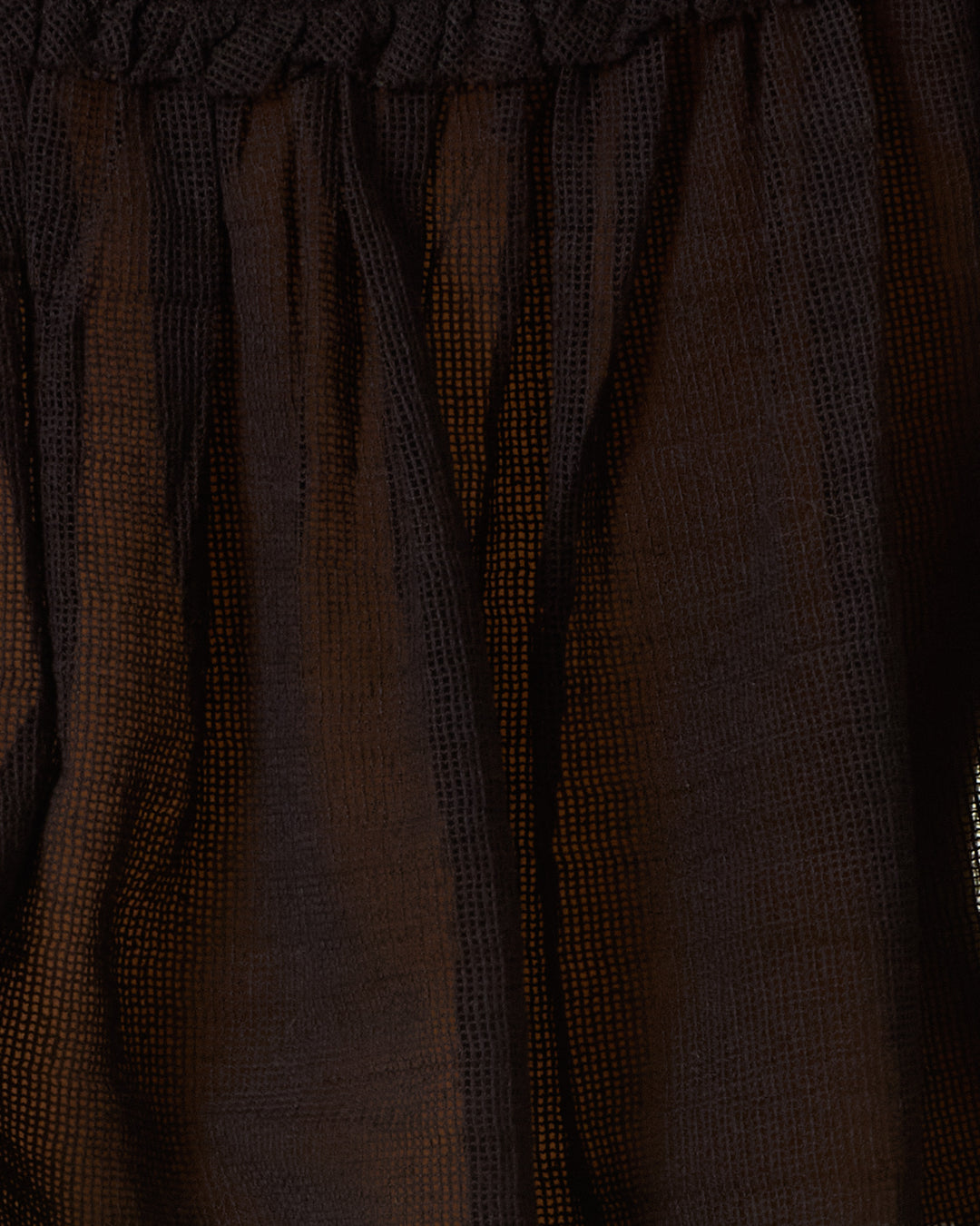 Close-up of the Tati Onyx Weave Top, featuring dark brown cotton mesh fabric with a textured, grid-like weave and gathered elastic at the top.