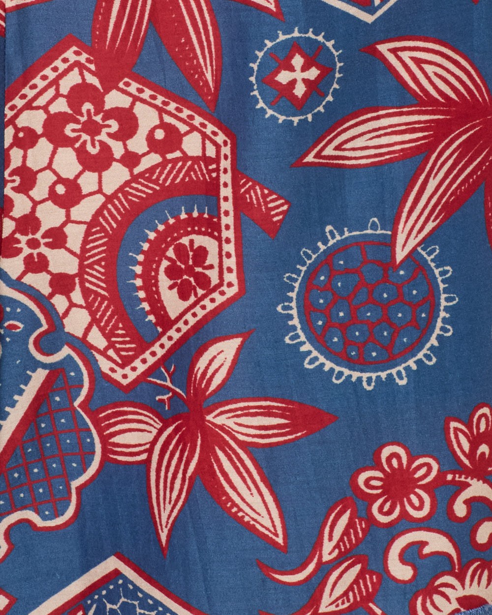 The Tillie Delft Hive Short features red and cream floral and geometric patterns on a blue background, inspired by vintage wagara prints with bold stylized flowers, circles, and shapes for a decorative look.
