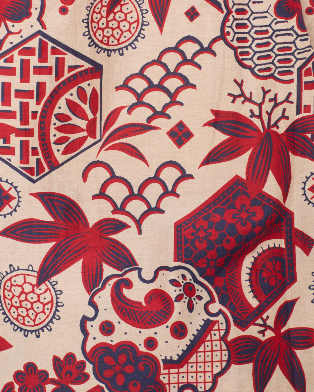 The Winnie Crimson Hive Shirt features a soft cotton-silk blend with a cream base and repeating red and navy geometric, floral, and abstract patterns.