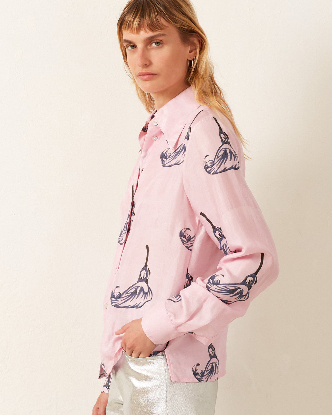 A person wearing the Dolly Pink Calla Lily Shirt paired with silver pants, standing against a plain backdrop.