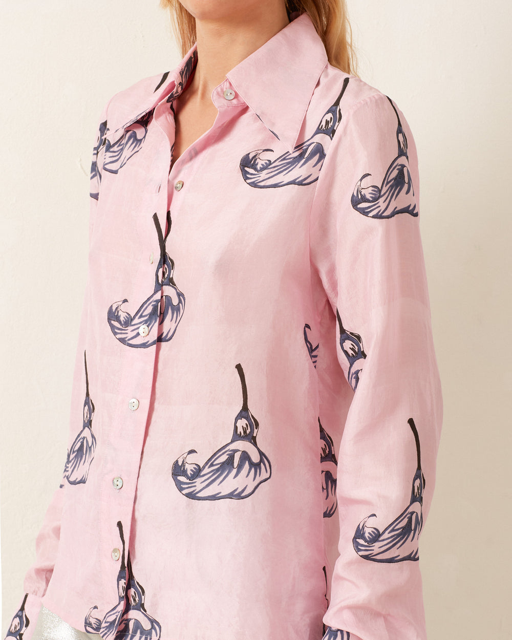 A person wearing a Dolly Pink Calla Lily Shirt with a pattern of stylized flowers, reminiscent of a vintage-inspired floral shirt.