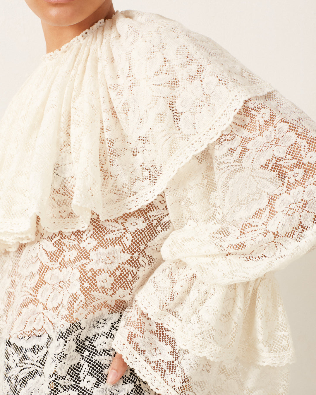 Close-up of a person wearing the Eloise Magnolia Lace Top, featuring white floral lace with ruffled details that exude a vintage feel.