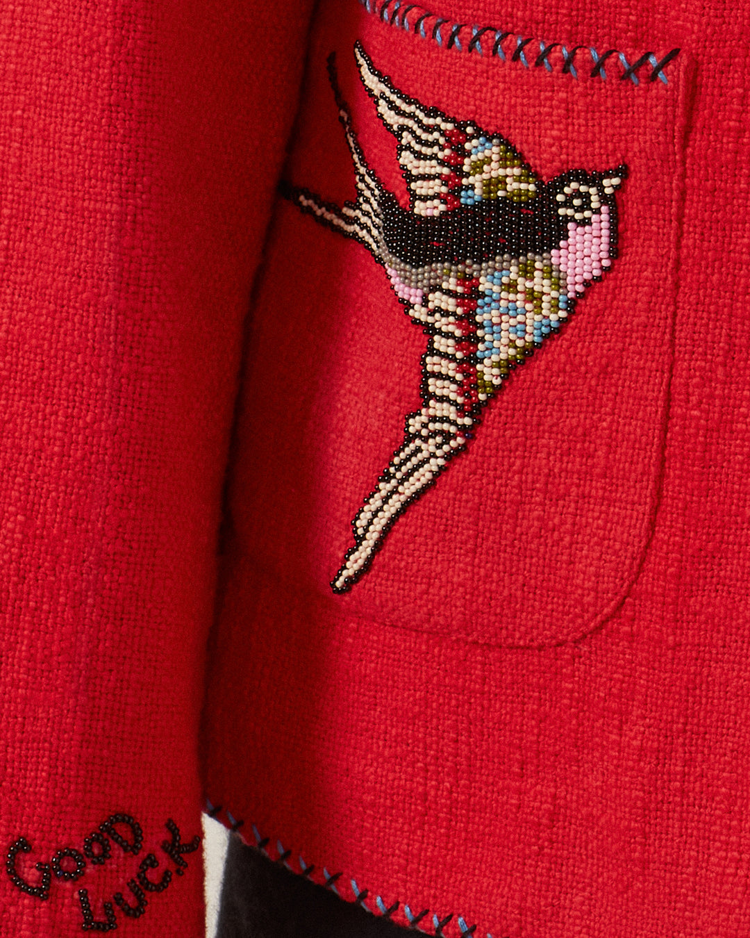 The Francis Crimson Tattoo Jacket exudes a vintage vibe with its embroidered bird design on the pocket. The phrase "Good Luck" is stitched at the bottom in black, enhancing the charm of this captivating piece.