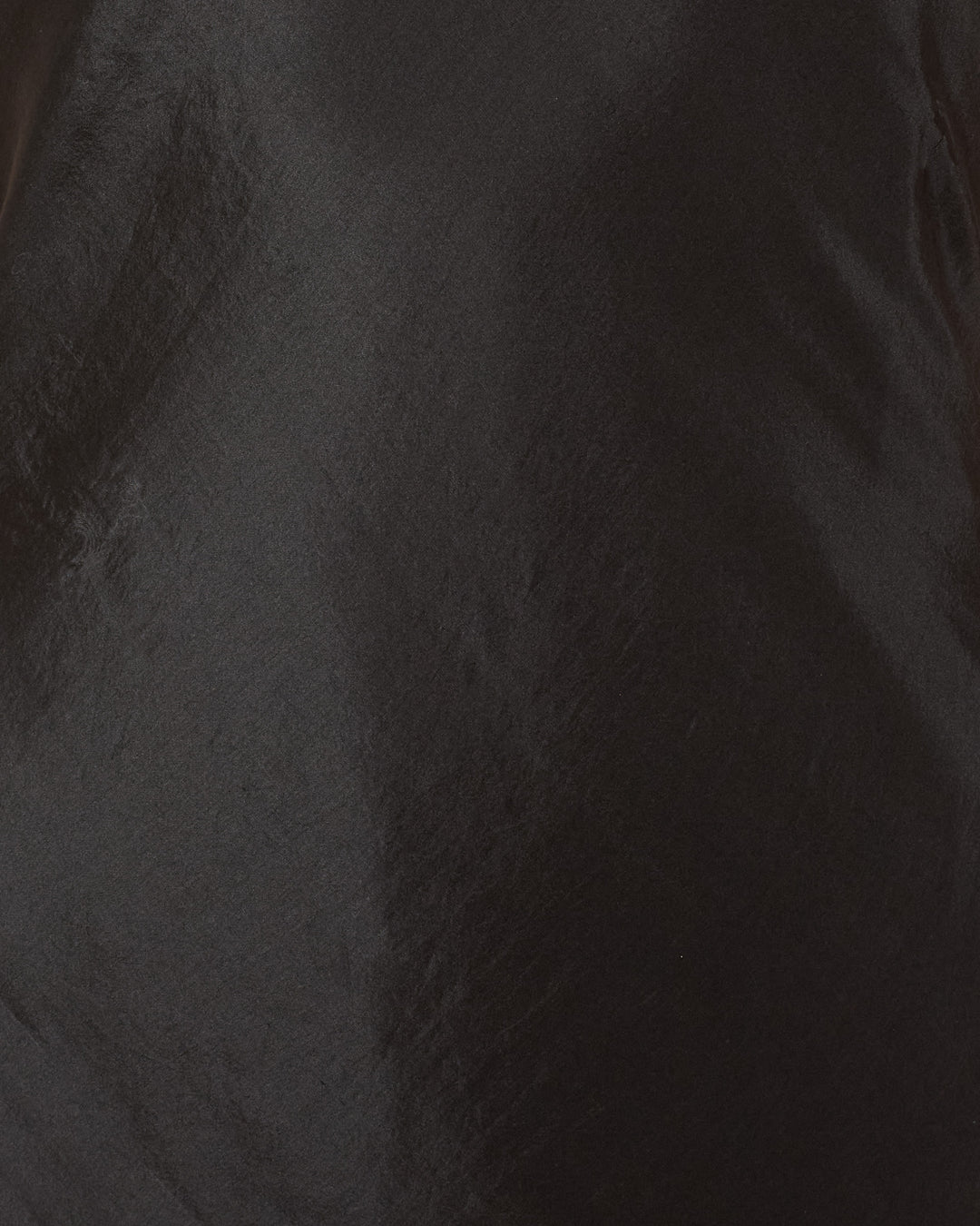 Close-up of the Adele Gilded Coin Dress’s smooth, shiny black fabric with subtle light reflections and soft folds, highlighting the luxurious texture and artisan craftsmanship.