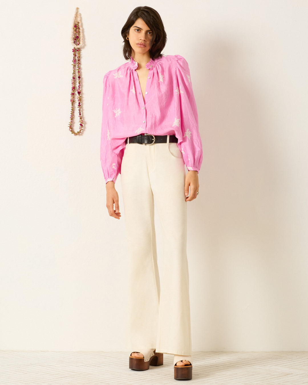 A woman stands in the Annabel Pink Jasmine Shirt, a hand-loomed silk top in a soft pink shade.