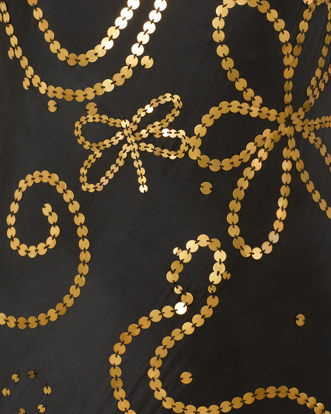 Close-up of the Athens Jet Coin Silk Dress, featuring black fabric adorned with shiny gold sequin embroidery in swirling and floral, Klimt-inspired motifs.