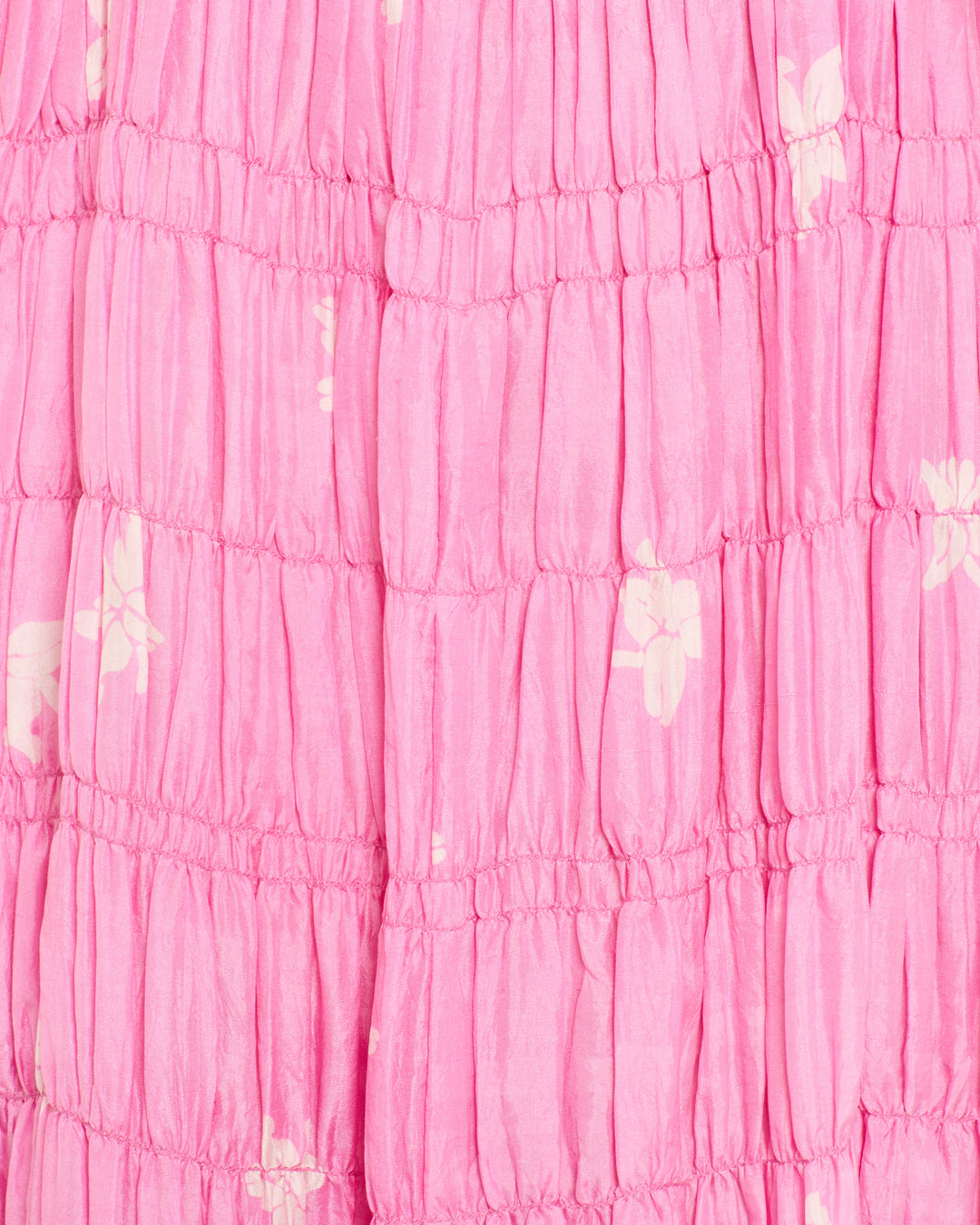 Close-up of pink ruched fabric with a subtle white floral pattern from the artisan handmade Emrys Pink Jasmine Dress.