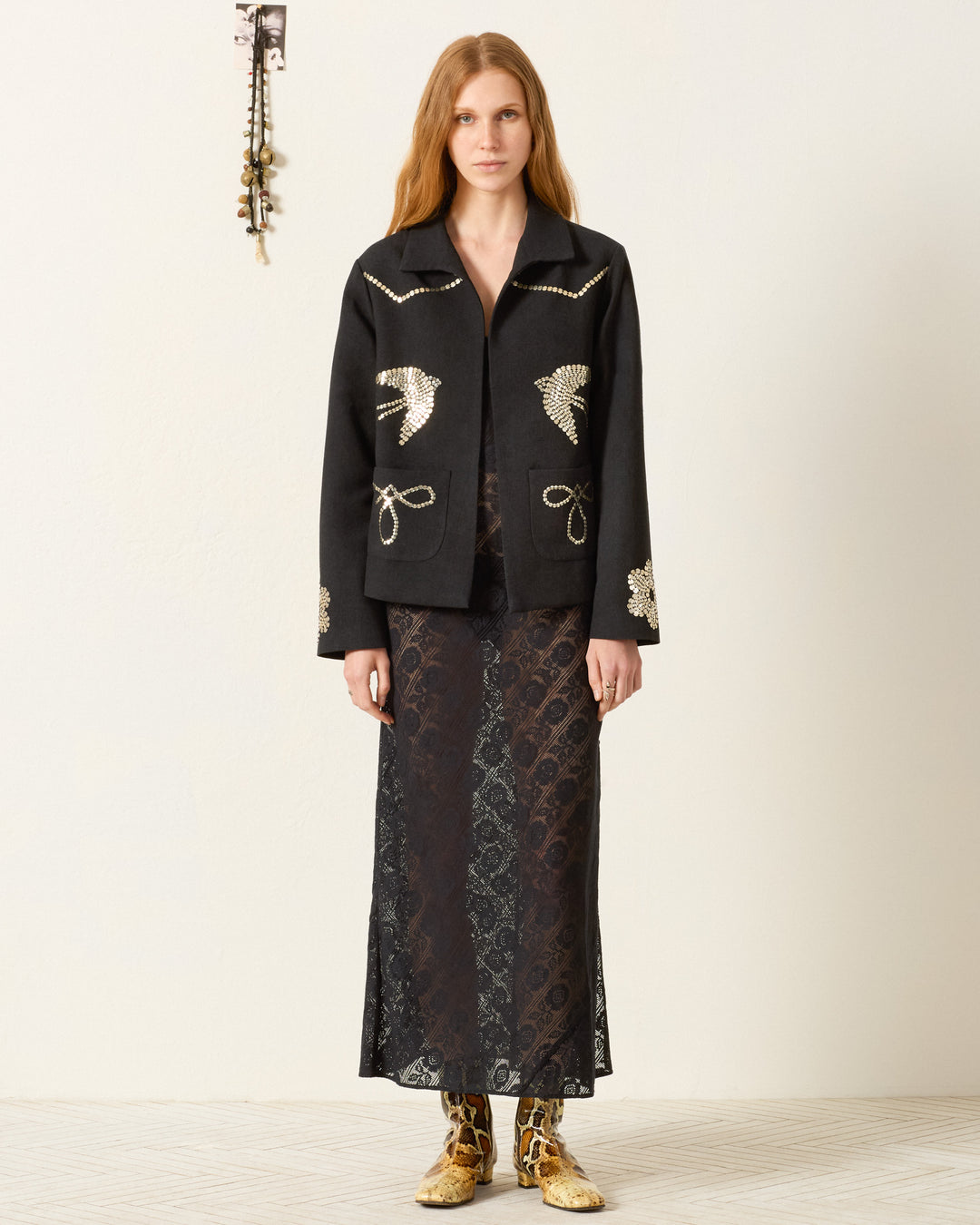 A woman wears the Francis Lovebird Coin Jacket over a sheer, patterned black dress and yellow patterned boots, standing against a plain background.